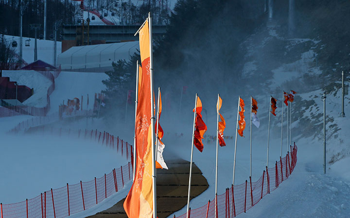 Flags and snow blow in the wind after the men's downhill was postponed due to high winds at the 2018 Winter Olympics in Jeongseon, South Korea, Feb. 11, 2018. 