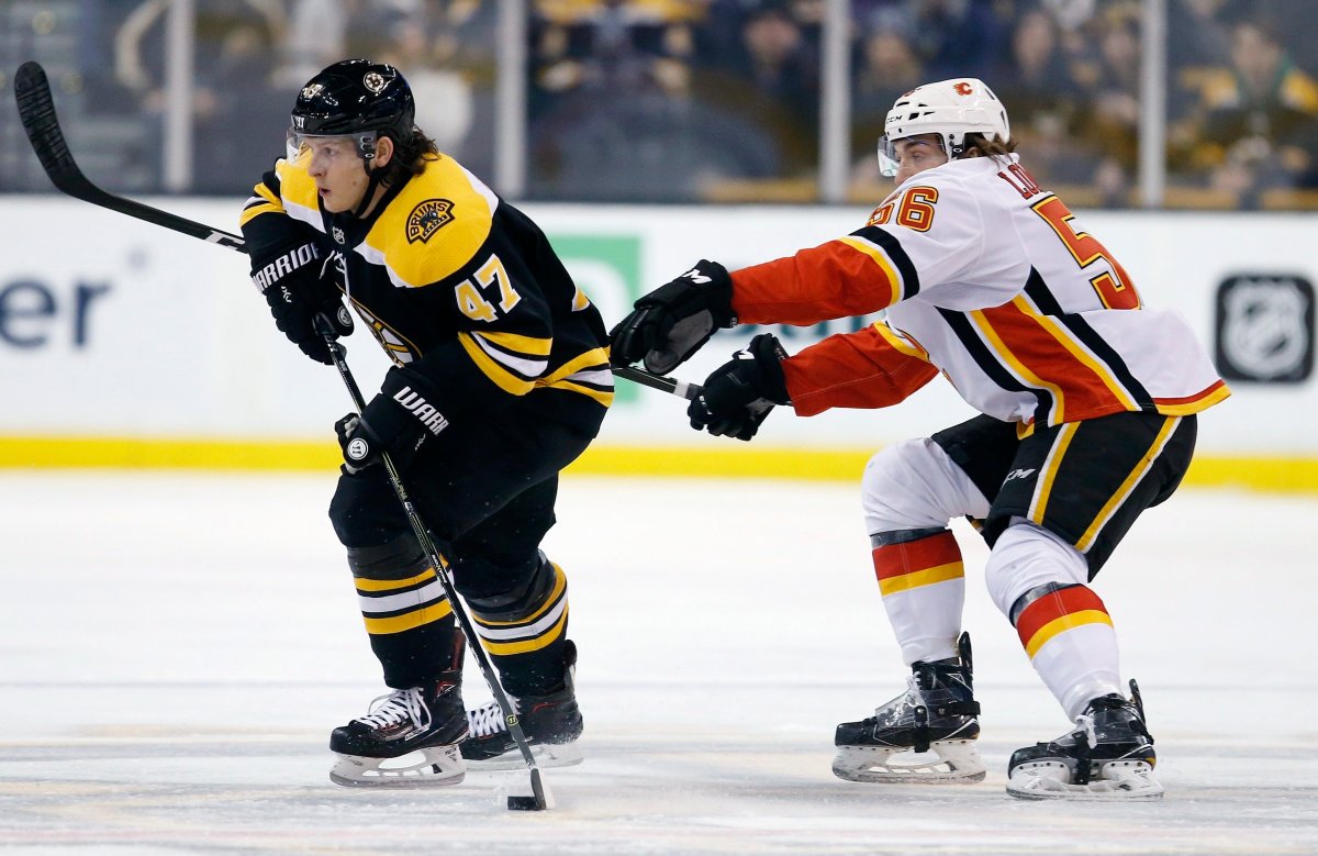 Calgary Flames' Ryan Lomberg (56) battles Boston Bruins' Torey Krug (47) for the puck during the first period of an NHL hockey game in Boston, Tuesday, Feb. 13, 2018. (AP Photo/Michael Dwyer).