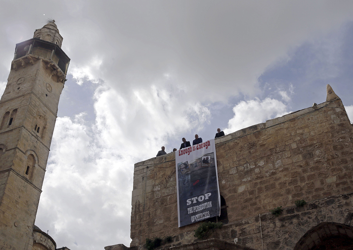 A protest sign hangs outside of the Church of the Holy Sepulchre, traditionally believed by many Christians to be the site of the crucifixion and burial of Jesus Christ, in Jerusalem, Sunday, Feb. 25, 2018. 