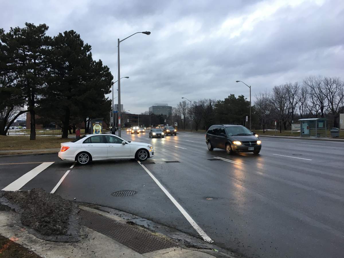 A driver tries to turn left from Kern Road onto Don Mills Road during rush hour .