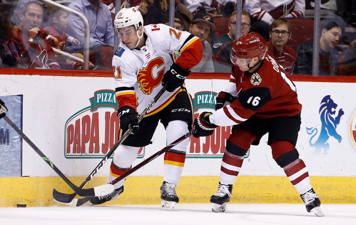 Calgary Flames right wing Garnet Hathaway (21) battles with Arizona Coyotes left wing Max Domi (16) for the puck during the first period of an NHL hockey game Thursday, Feb. 22, 2018, in Glendale, Ariz. (AP Photo/Ross D. Franklin).