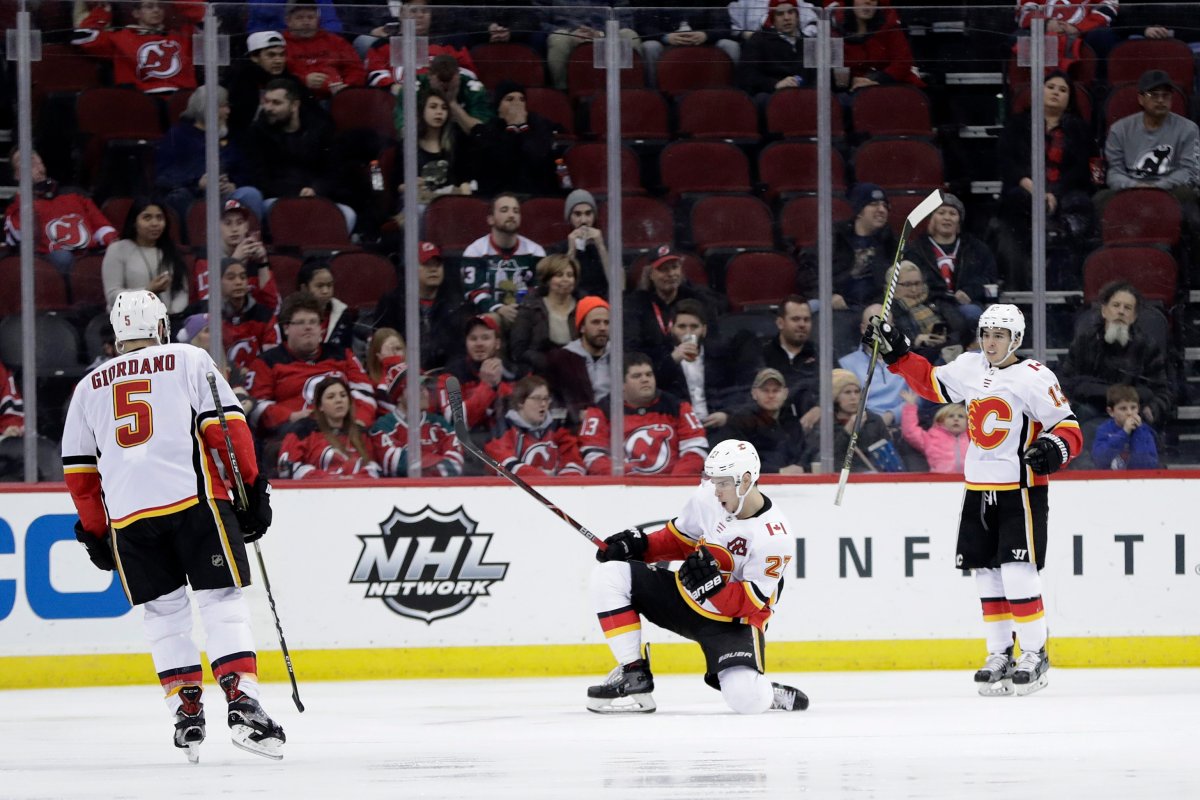 Calgary Flames center Sean Monahan, center, celebrates his goal against the New Jersey Devils during the second period of an NHL hockey game, Thursday, Feb. 8, 2018, in Newark, N.J. Flames' Mark Giordano (5) and Johnny Gaudreau (13) look on. (AP Photo/Julio Cortez).