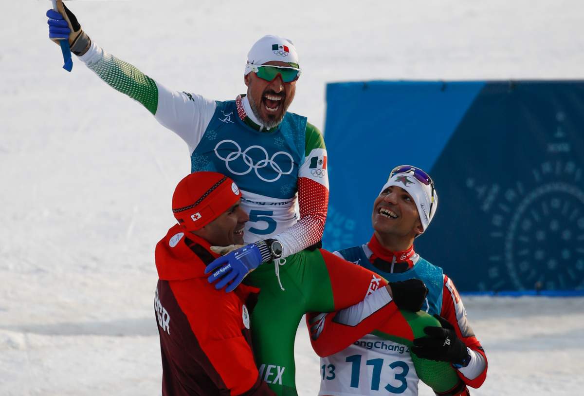 Tonga’s Pita Taufatofua (L) and Morocco’s Samir Azzimani (R) lift Mexico’s German Madrazo onto their shoulders as they celebrate at the finish line in the men’s 15 km cross-country freestyle during the Pyeongchang 2018 Winter Olympic Games on Feb. 16, 2018 in Pyeongchang.