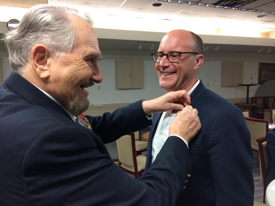 Bruce Stock, the Public Relations Officer for Zone A-6, gives Mayor Matt Brown his associate member pin.