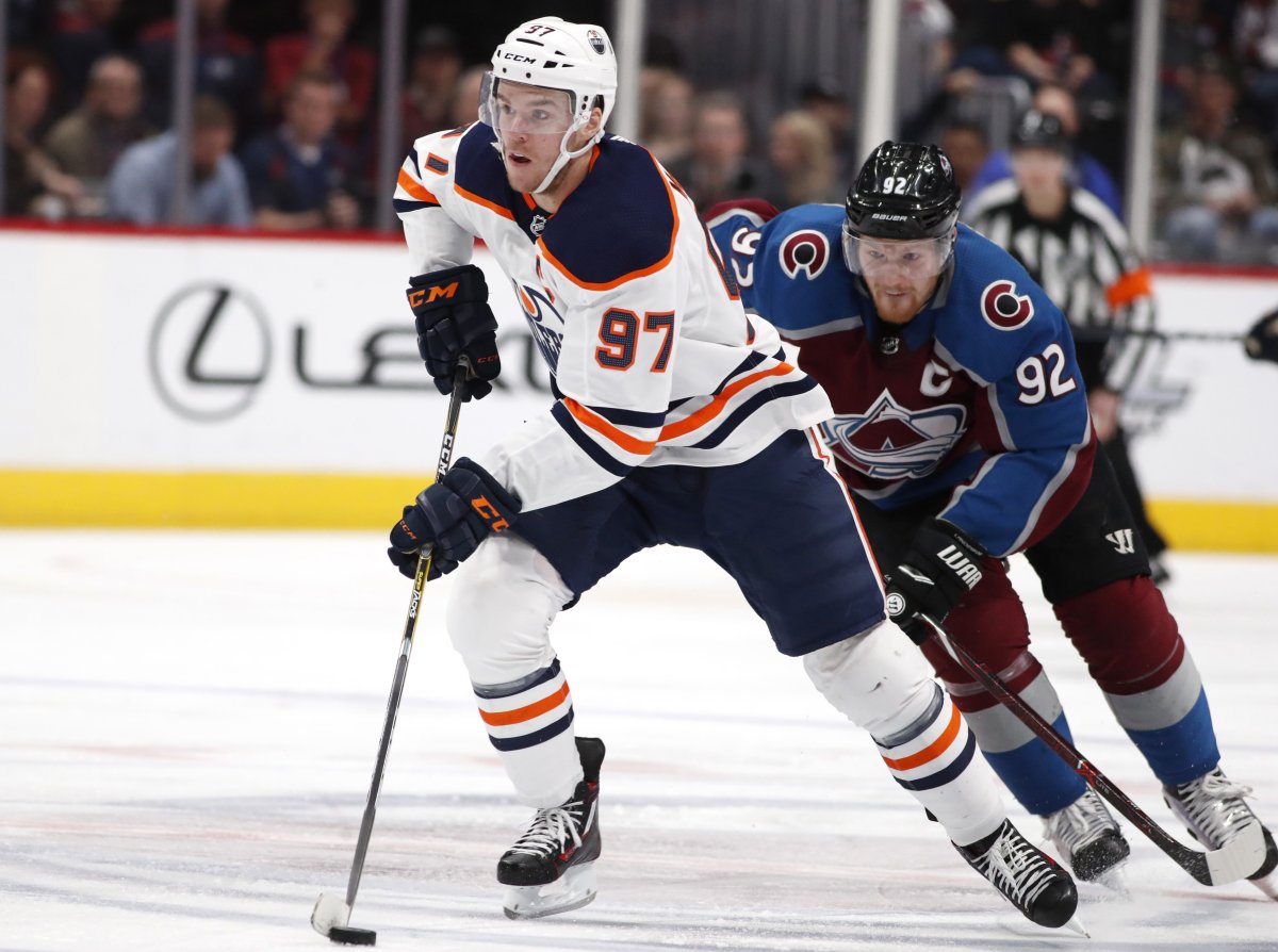 Edmonton Oilers center Connor McDavid, front, drives downice with the puck as Colorado Avalanche left wing Gabriel Landeskog pursues in the second period of an NHL hockey game Sunday, Feb. 18, 2018, in Denver. 