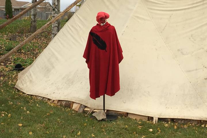 A silhouette representing missing and murdered women stands outside a sacred fire on the Membertou First Nation in Nova Scotia during the MMIWG hearings there in October 2017. 