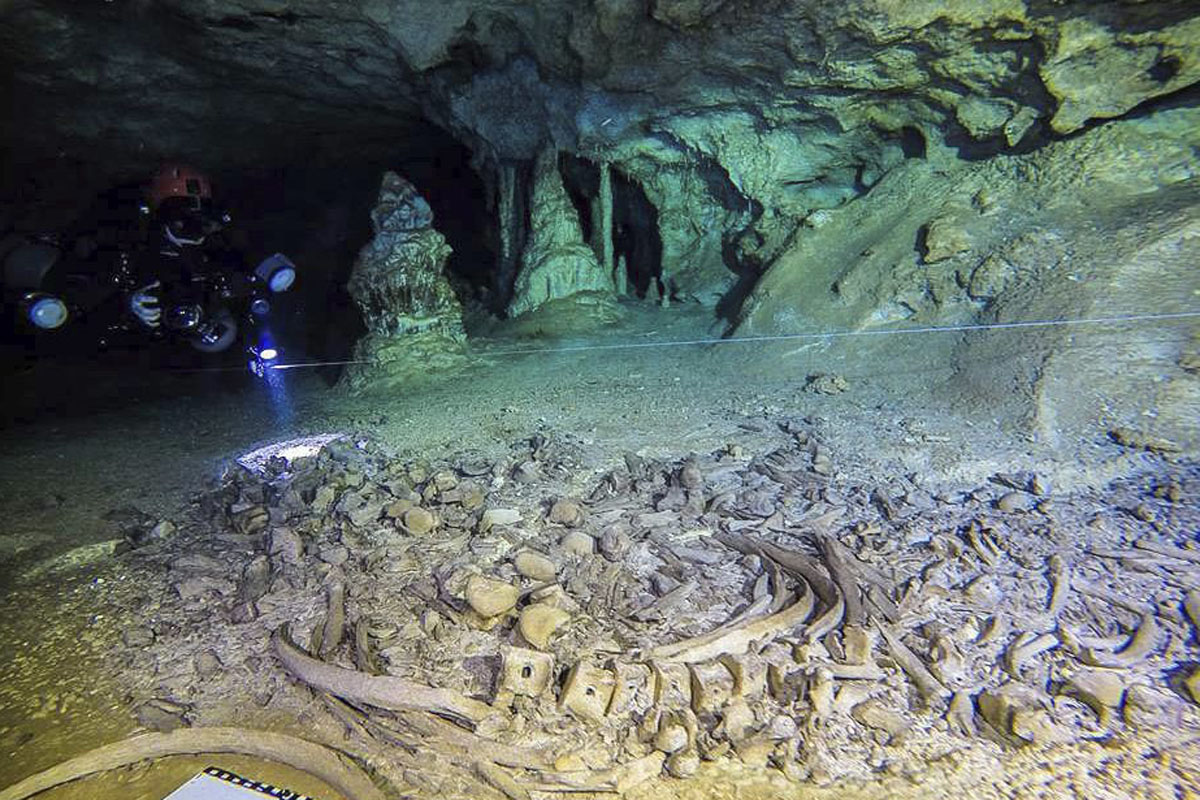 This undated photo released by Mexico’s National Anthropology and History Institute (INAH) shows divers from the Great Mayan Aquifer project, left, exploring the Sac Actun underwater cave system, where Mayan and Pleistocene bones and cultural artifacts have been found submerged, near Tulum, Mexico.