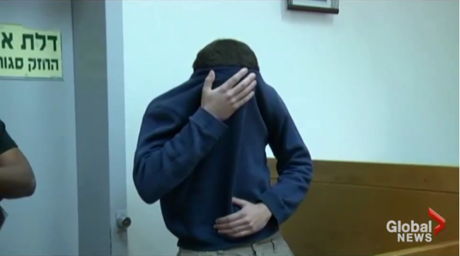 Suspect Michael Kadar covers his face in this screen grab from a video taken March 23, 2017 following his arrest in Israel.