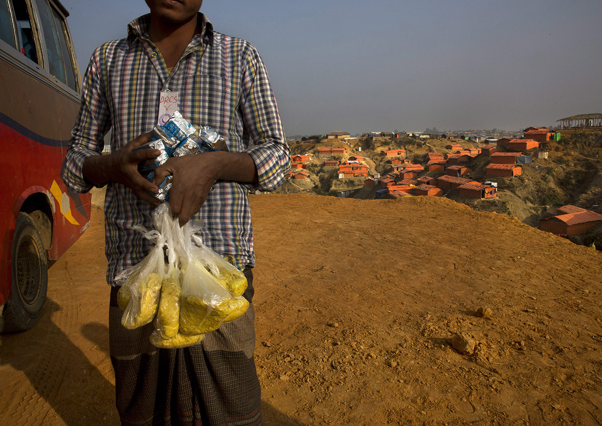 In this Wednesday, Jan. 17, 2018, photo, a newly arrived Rohingya refugee Muslim carries high power protein biscuits and Khicdhi, made from rice and lentils, for his family after arriving at Balukhali refugee camp near Cox's Bazar, Bangladesh. 