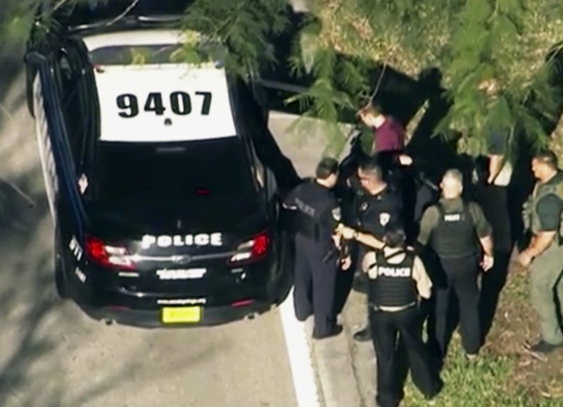 In this frame grab from video provided by WPLG-TV, law enforcement personnel arrest an unidentified man (in dark red), following a shooting at Marjory Stoneman Douglas High School in Parkland.