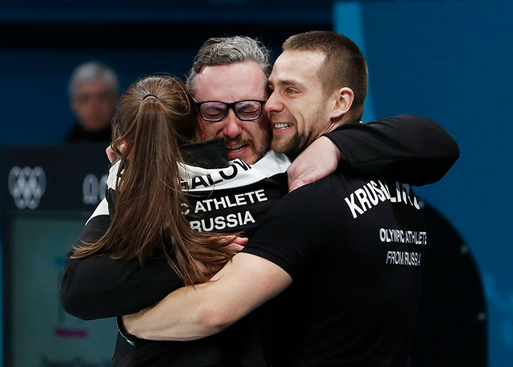 Aleksandr Krushelnitckii and Anastasia Bryzgalova, Olympic athletes from Russia, hug their coach Vasily Gudin after winning the bronze in mixed doubles curling. 