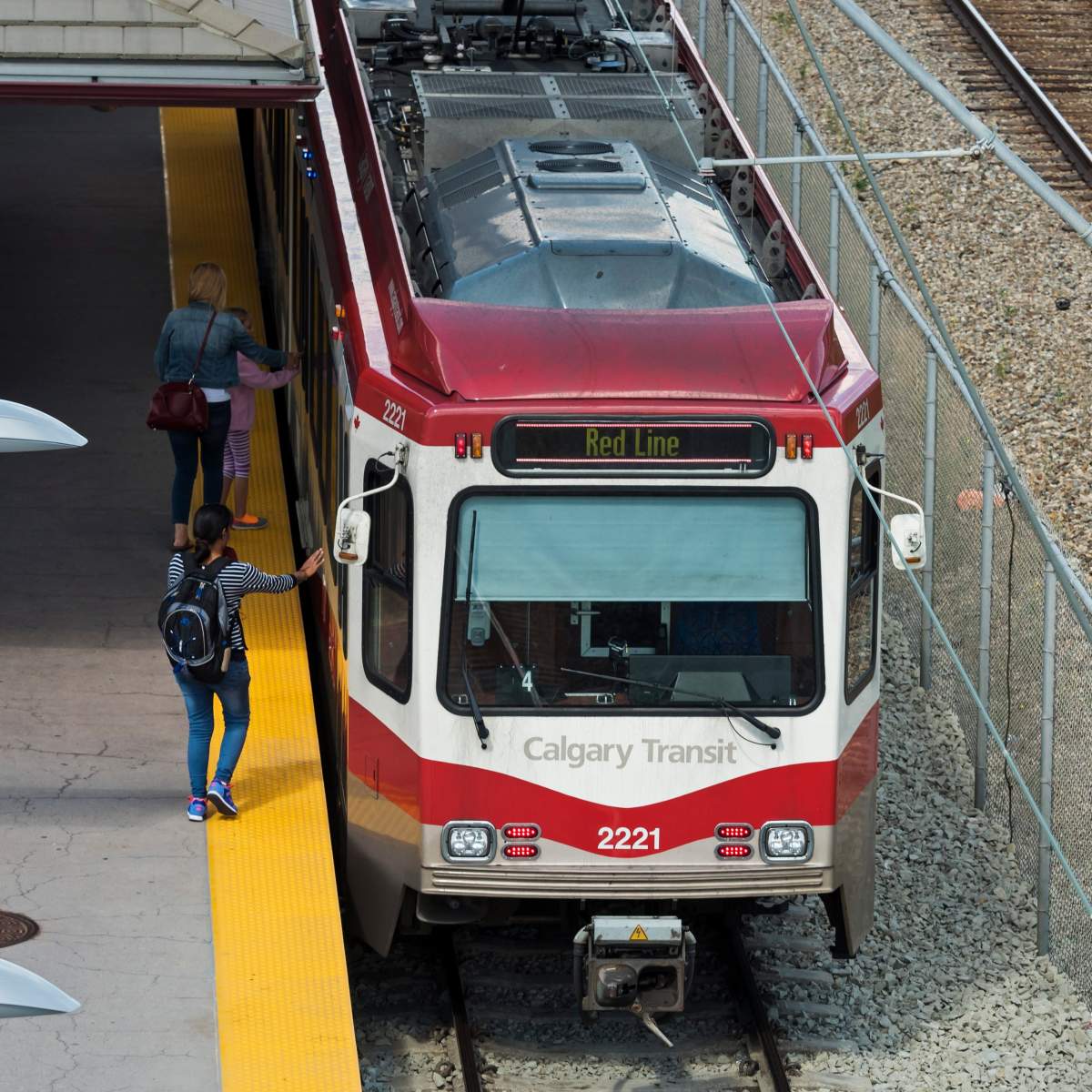 Commuters board a Calgary Transit (CTS) light rail (LRT) C-Train at Fish Creek-Lacombe station on the transit system's "Red Line."