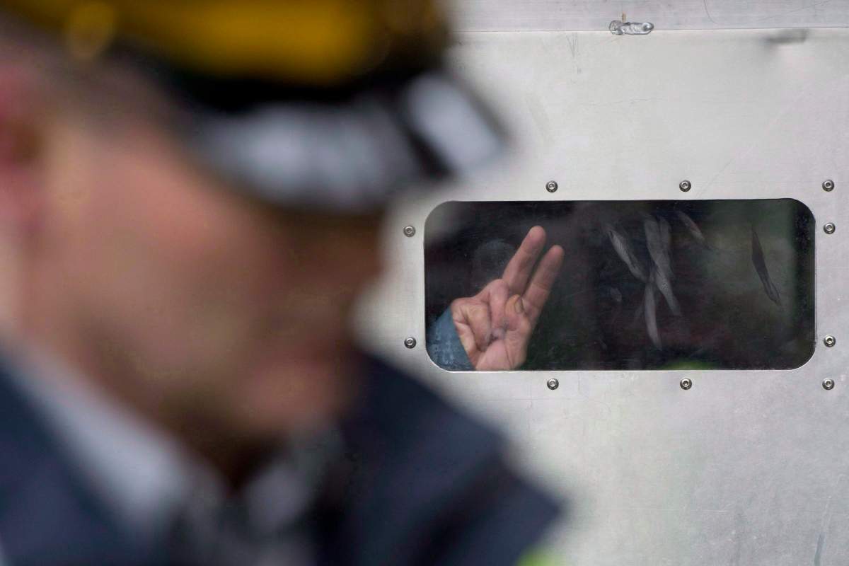 A protester flashes a peace sign from inside a paddy wagon after being taken into custody at an anti-pipeline demonstration in Burnaby, B.C., on Thursday, Nov. 20, 2014. 