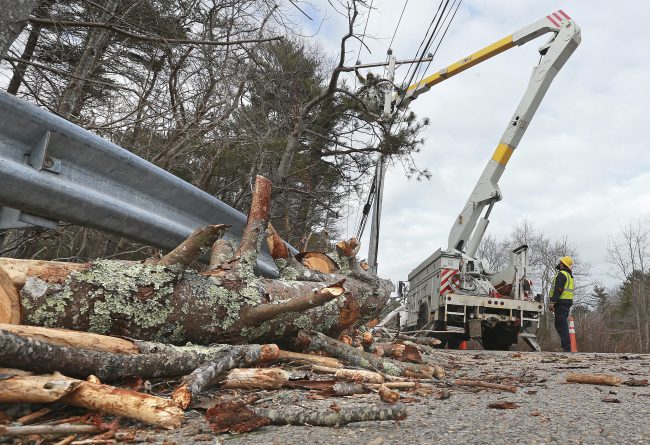 A lineman repairs utility lines from a bucket truck along Route 3A in Marshfield, Mass., in the aftermath of a nor'easter storm on Sunday, March 4, 2018. 