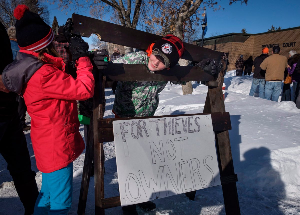 A young boy and girl play with homemade stocks as people gather in support of Edouard Maurice outside court in Okotoks, Alta., Friday, March 9, 2018.