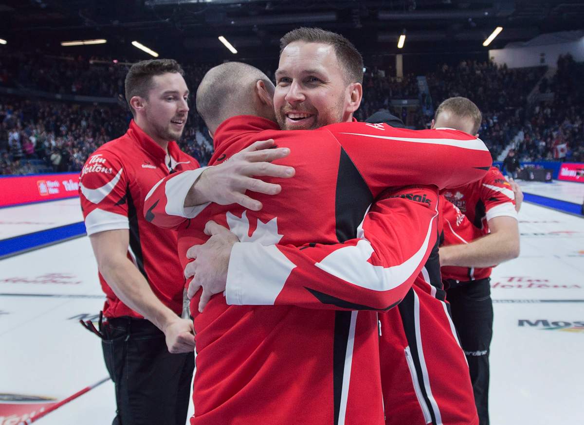 Team Canada skip Brad Gushue embraces alternate Tom Sallows after defeating Alberta 6-4 to win the Tim Hortons Brier at the Brandt Centre in Regina on Sunday, March 11, 2018.