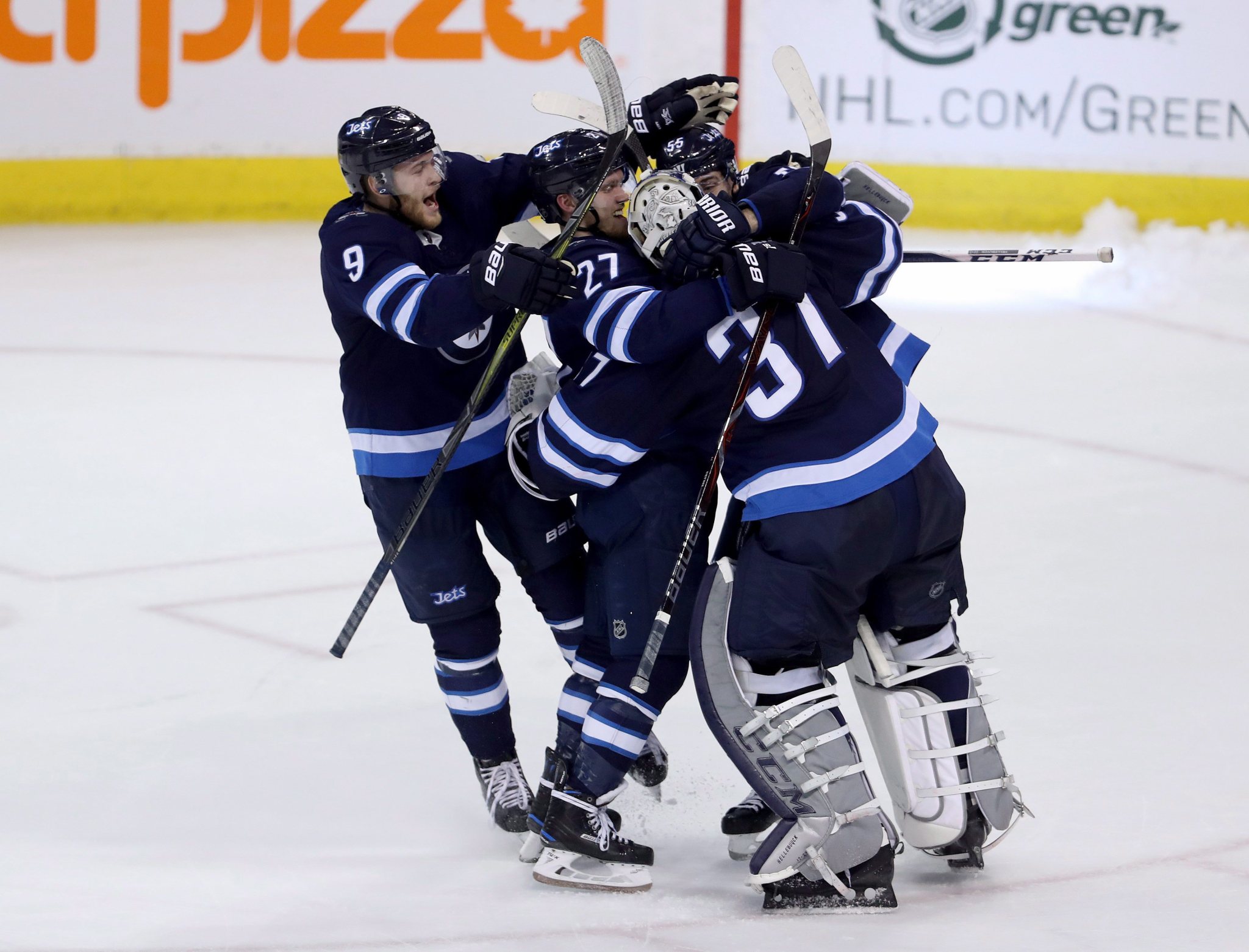 Winnipeg Jets' Andrew Copp (9), Nikolaj Ehlers (27) and Mark Scheifele (55) rush to goaltender Connor Hellebuyck (37) after he made the game-winning save against the Nashville Predators during the shootout following NHL hockey action in Winnipeg, Sunday, March 25, 2018. THE CANADIAN PRESS/Trevor Hagan.