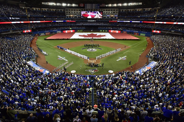 Baseball fans stand during the national anthems before the American League baseball game between the New York Yankees and the Toronto Blue Jays in Toronto, Thursday, March 29, 2018. THE CANADIAN PRESS/Frank Gunn.