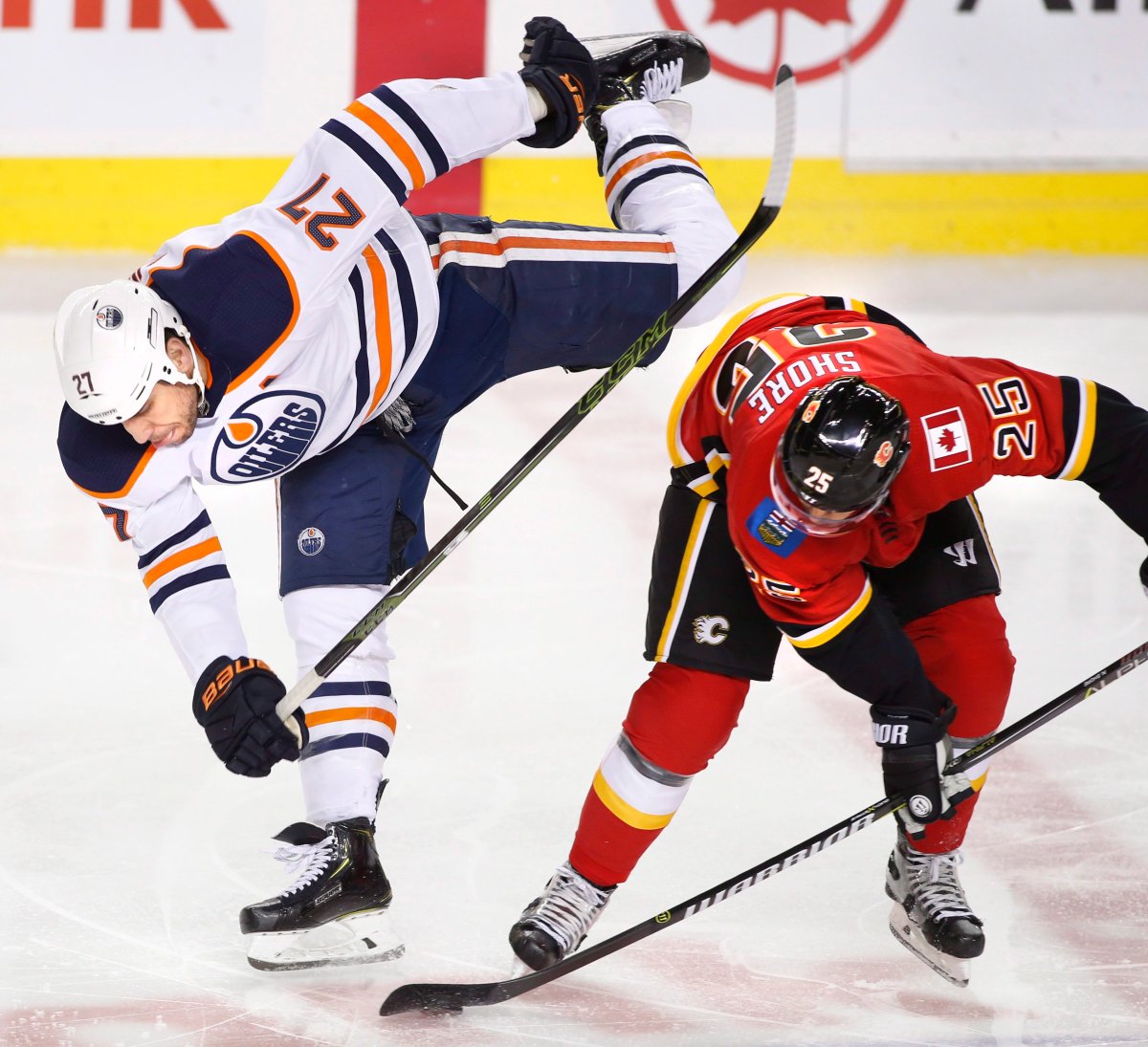 Edmonton Oilers' Milan Lucic (27) is sent flying by Calgary Flames' Nick Shore (25) during second period NHL action in Calgary on Saturday, March 31, 2018. THE CANADIAN PRESS/Larry MacDougal.