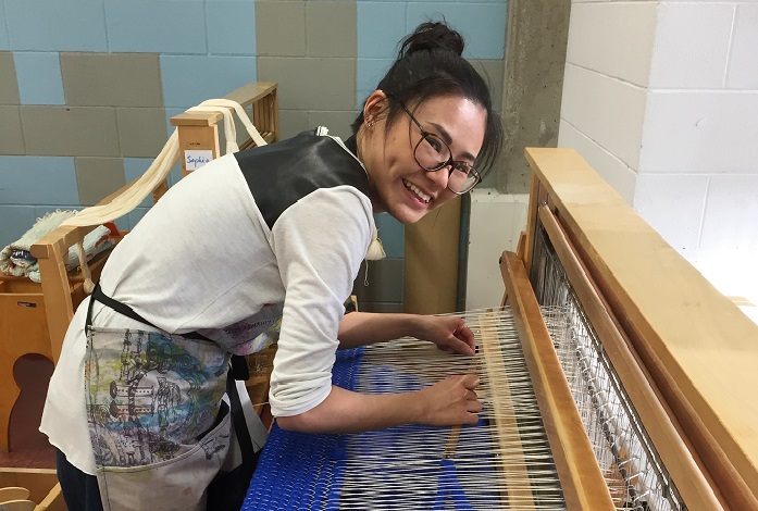 ACAD student Yilu Xing working on the sweater for Kensington’s Chicken on the Way chicken statue.