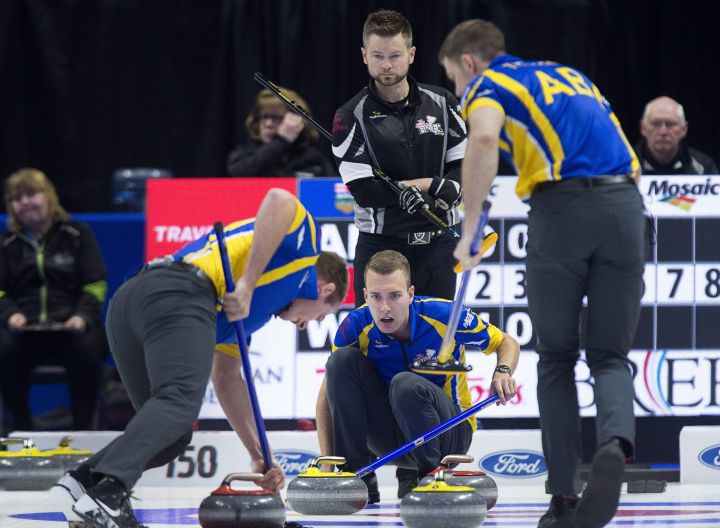 Mike McEwen, skip of the wild card team from Winnipeg, looks on as Alberta skip Brendan Bottcher, second Brad Thiessen, left, and lead Karrick Martin, right, bring a rock into the house at the Tim Hortons Brier curling championship at the Brandt Centre in Regina on Wednesday, March 7, 2018. 