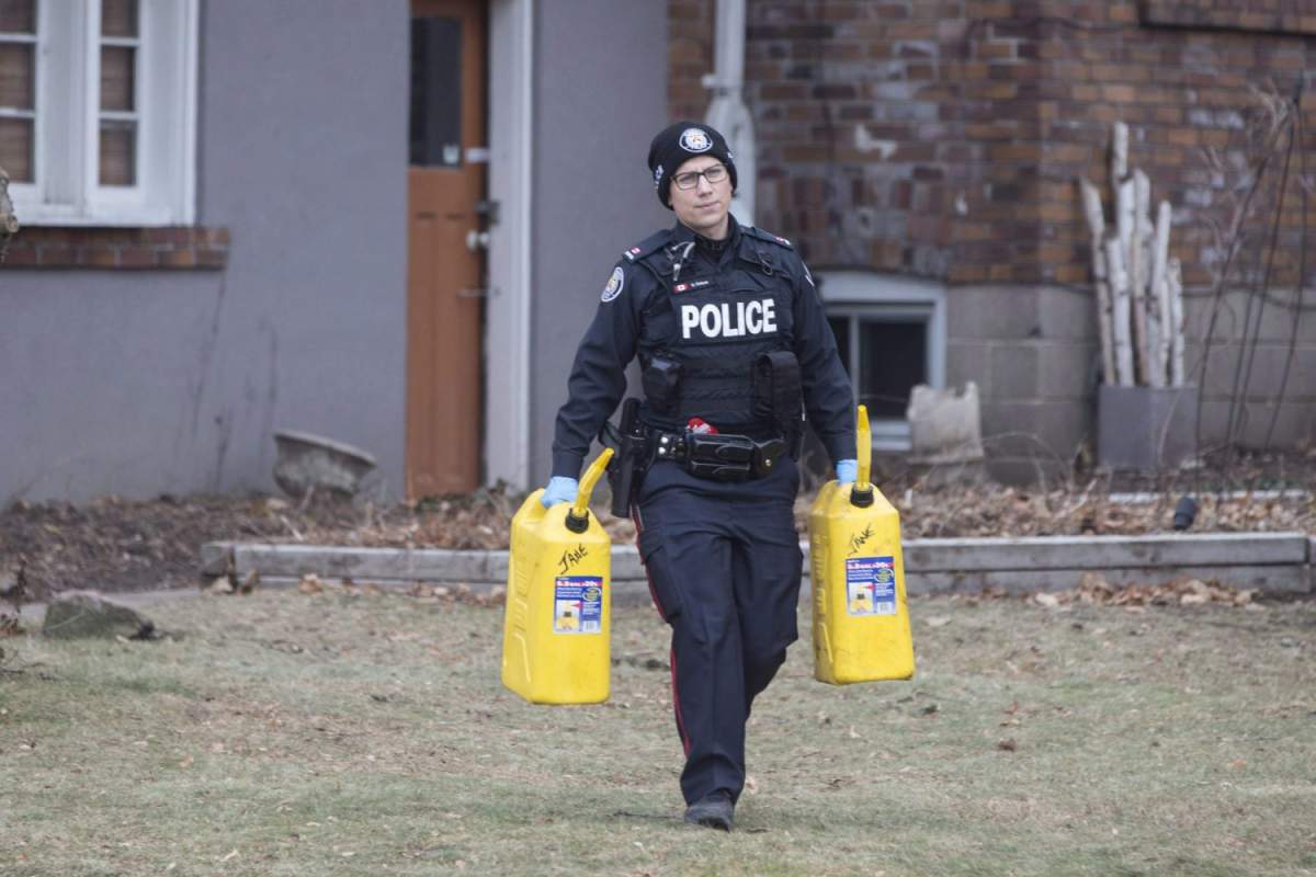 A police officer carries containers outside a house on Mallory Crescent in Toronto, where Bruce McArthur did landscape work, on Monday, January 29 , 2018.