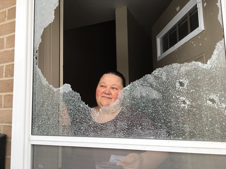 Cindy looks through the shattered pane of glass in her screen door. London police are investigating gun shots in the east-end housing complex where she lives. 