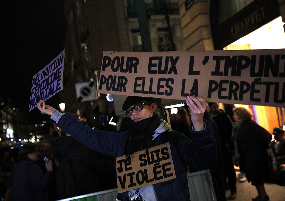 A activist holds a banner reading: "For him impunity, for her a life sentence" during a protest in Paris, Tuesday, Nov. 14, 2017. Justice Minister Nicole Belloubet provoked consternation and dismay among feminist groups by saying a legal minimum age of 13 for sexual consent "is worth considering.".