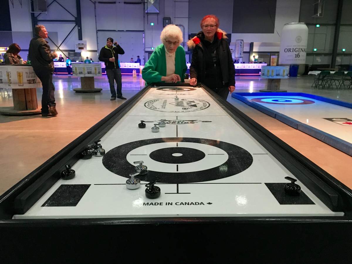 Margaret Scott (left) throws a rock during a friendly game of table curling against Debra Leask in the Brier Patch at the International Trade Centre in Regina, Sask.