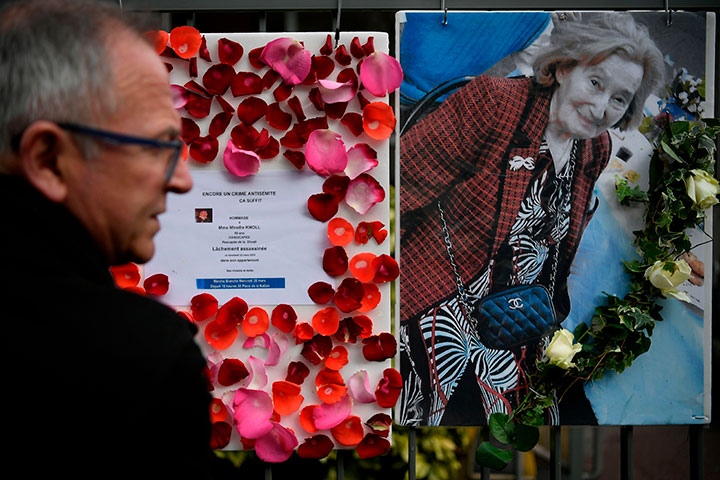 A man stands in front of a picture of Mireille Knoll and a message announcing a silent march, condemning the alleged anti-Semitic motive for her killing in Paris on March 27, 2018. 
