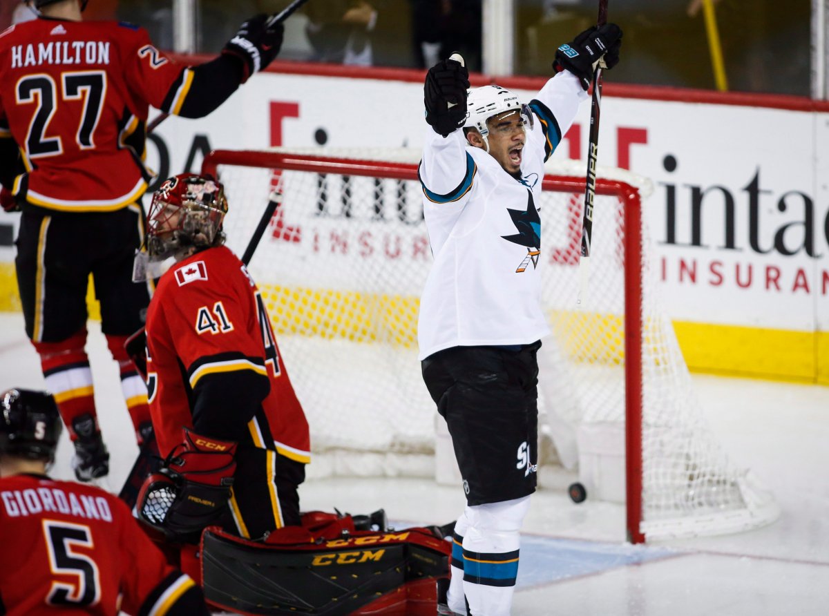 San Jose Sharks left wing Evander Kane (9) celebrates his fourth goal as Calgary Flames goaltender Mike Smith (41) looks away during third period NHL hockey action in Calgary, Friday, March 16, 2018. THE CANADIAN PRESS/Jeff McIntosh.