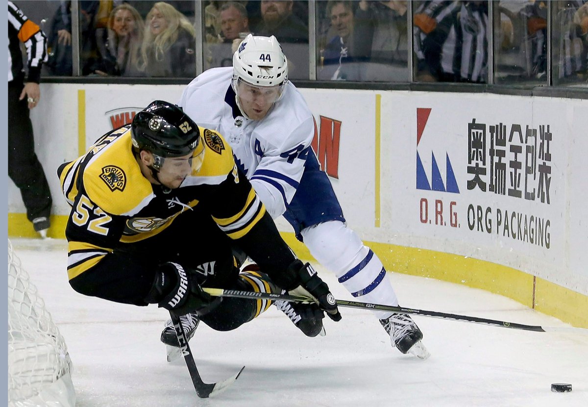 Toronto Maple Leafs defenseman Morgan Rielly (44) trips Boston Bruins center Sean Kuraly (52) who was making a play for the puck behind the net during the second period of an NHL hockey game, Saturday, Feb. 3, 2018, in Boston. (AP Photo/Mary Schwalm).