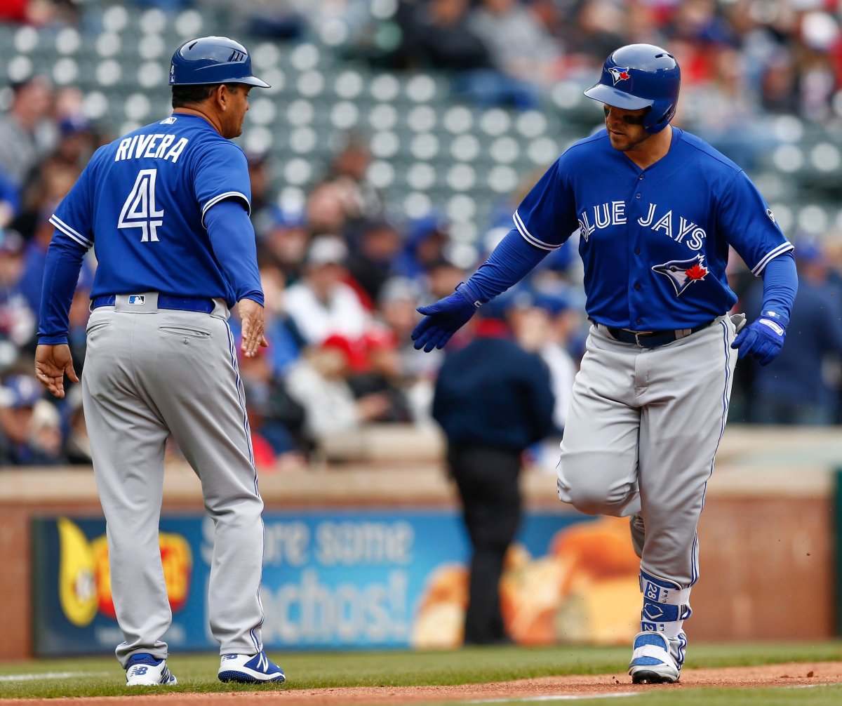Toronto Blue Jays' Steve Pearce, right, is congratulated by third base coach Luis Rivera (4) as he rounds the bases on his home run off the first pitch thrown by Texas Rangers starting pitcher Cole Hamels during the first inning of a baseball game, Sunday, April 8, 2018, in Arlington, Texas.