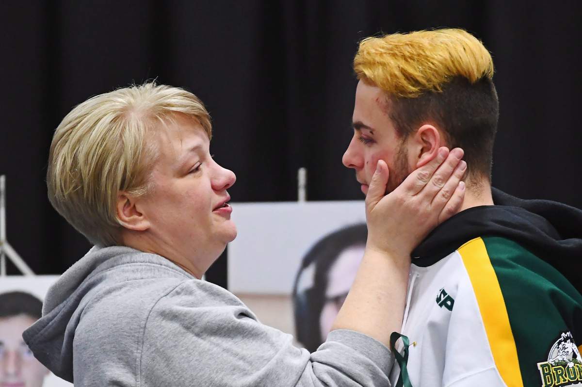 Humboldt Broncos’ Nick Shumlanski, who was released from hospital earlier today, is comforted by a mourner during a vigil at the Elgar Petersen Arena, home of the Humboldt Broncos, to honour the victims of a fatal bus accident in Humboldt, Sask. on Sunday, April 8, 2018. THE CANADIAN PRESS/Jonathan Hayward