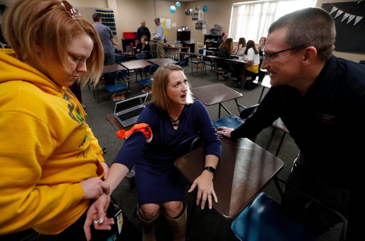 In this March 28, 2018, photo, Dr. Richard Sidwell, right, talks with Mary Owens, center, and Samantha Wing during a medical training session for teachers and staff at Southeast Polk High School in Pleasant Hill, Iowa. 