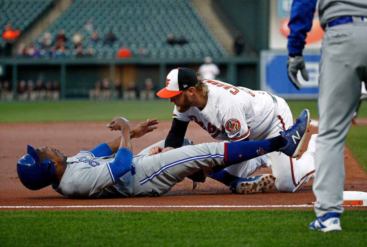 Baltimore Orioles starting pitcher Andrew Cashner, right, collides with Toronto Blue Jays' Curtis Granderson while tagging him after Granderson stole second base and then advanced to third in the first inning of a baseball game, Tuesday, April 10, 2018, in Baltimore. Granderson was sent back to first base due to a batter's interference call on Toronto's Justin Smoak. 