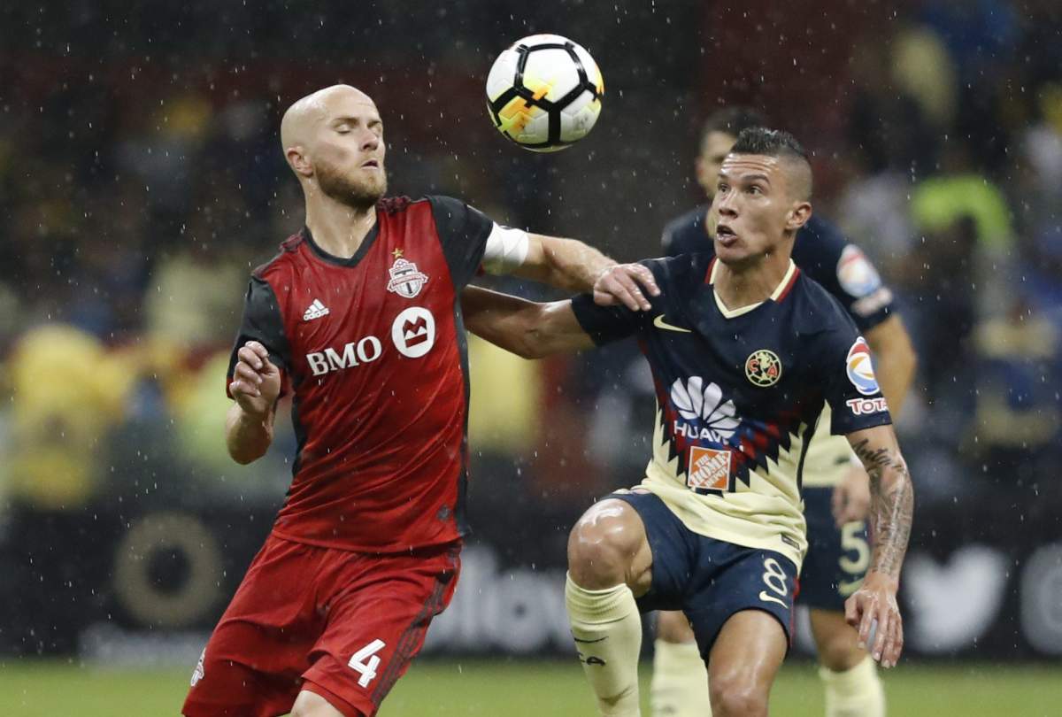 Matias Uribe (R) of America vies for the ball with Michael Bradley (L) of the Toronto FC during the second leg match of the semifinal of the CONCACAF Champions League, at the Azteca Stadium in Mexico City, Mexico, 10 April 2018.  