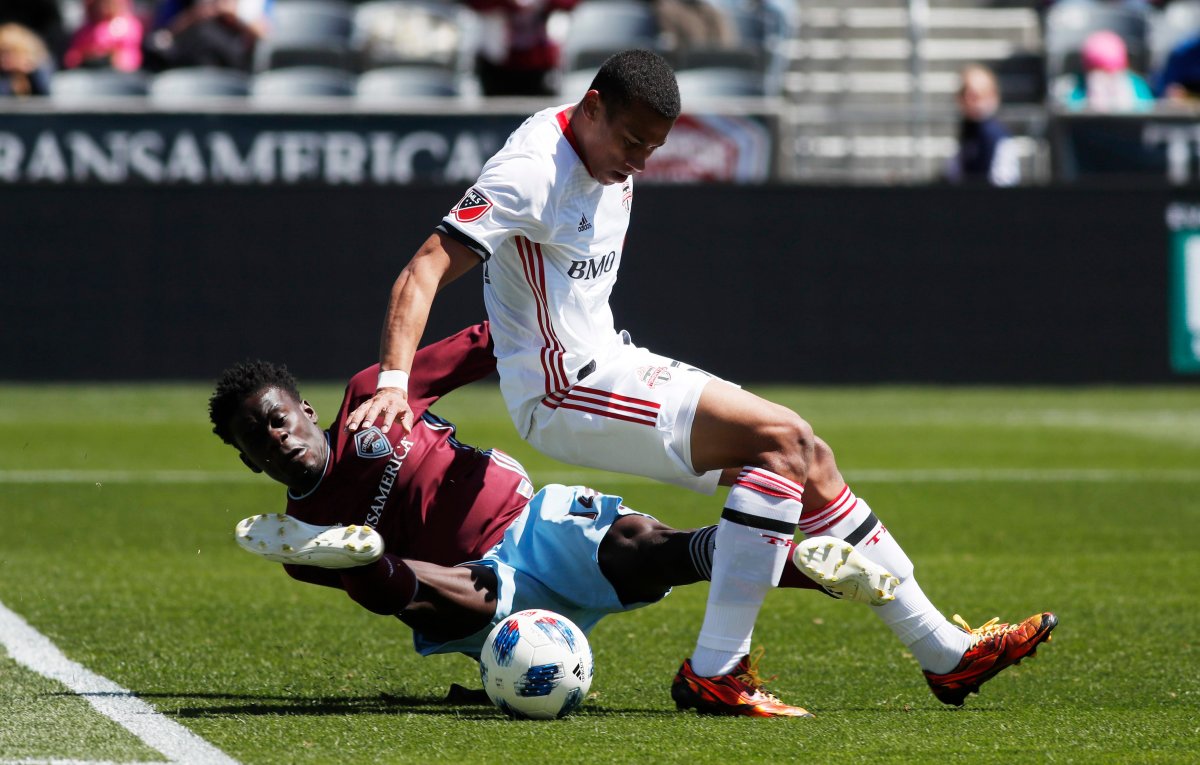 Toronto FC midfielder Ryan Telfer, front, gets tangled up with Colorado Rapids forward Dominique Badji as they fight for control of the ball in the first half of an MLS soccer match Saturday, April 14, 2018, in Commerce City, Colo.