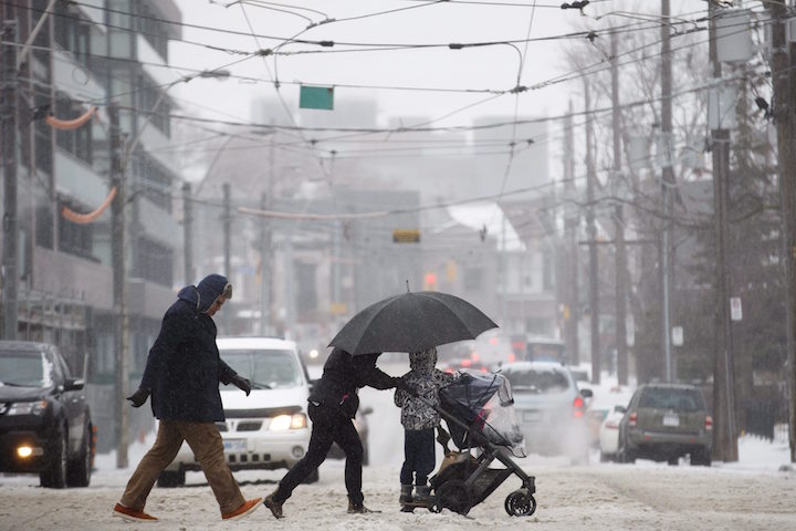 People cross the street as they trudge through falling hail, snow, and rain in Toronto, Ontario on Saturday, April 14, 2018. 