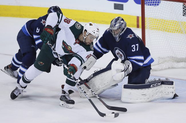 Minnesota Wild's Jordan Greenway (18) can't get the puck past Winnipeg Jets goaltender Connor Hellebuyck (37) during first period game five NHL playoff action in Winnipeg on Friday, April 20, 2018. 