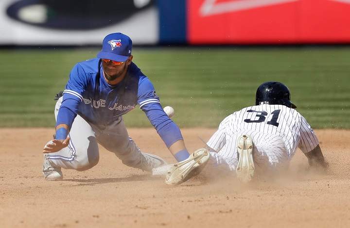 New York Yankees' Aaron Hicks, right, steals second base while Toronto Blue Jays shortstop Lourdes Gurriel tries to field a bad throw from catcher Russell Martin during the seventh inning of a baseball game at Yankee Stadium, Sunday, April 22, 2018, in New York. Gurriel count not control the ball and Hicks advanced to third base. 