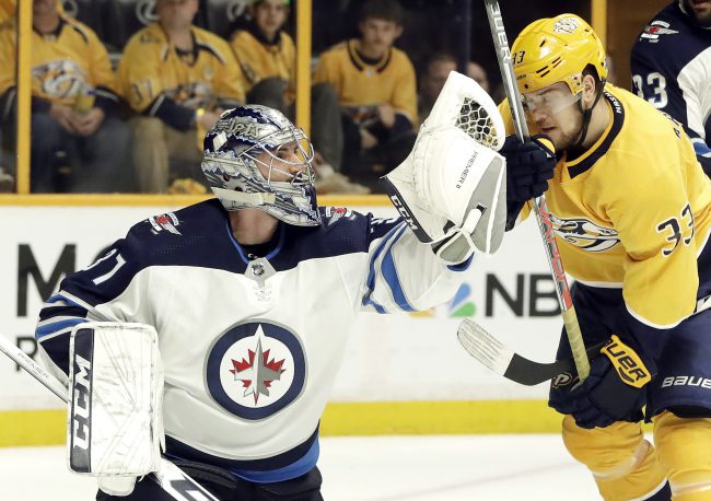 Winnipeg Jets goalie Connor Hellebuyck (37) catches the puck in front of Nashville Predators left wing Viktor Arvidsson (33), of Sweden, during the second period in Game 1 of an NHL hockey second-round playoff series Friday, April 27, 2018, in Nashville, Tenn. 