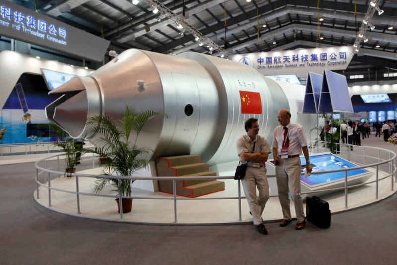 FILE - In this Nov. 16, 2010 file photo, visitors sit beside a model of China’s Tiangong-1 space station at the 8th China International Aviation and Aerospace Exhibition in Zhuhai, which is in southern China’s Guangdong Province.