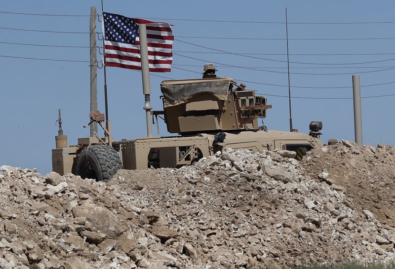 A U.S. soldier sits on an armored vehicle behind a sand barrier at a newly installed position near the tense front line between the U.S-backed Syrian Manbij Military Council and the Turkish-backed fighters, in Manbij, north Syria, Wednesday, April 4, 2018. 