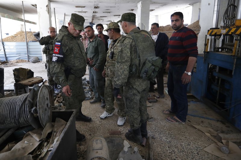 Russian military police officers check weapons left behind by members of the Army of Islam group in a factory produced weapons, in the town of Douma, the site of a suspected chemical weapons attack, near Damascus, Syria, Monday, April 16, 2018. 
