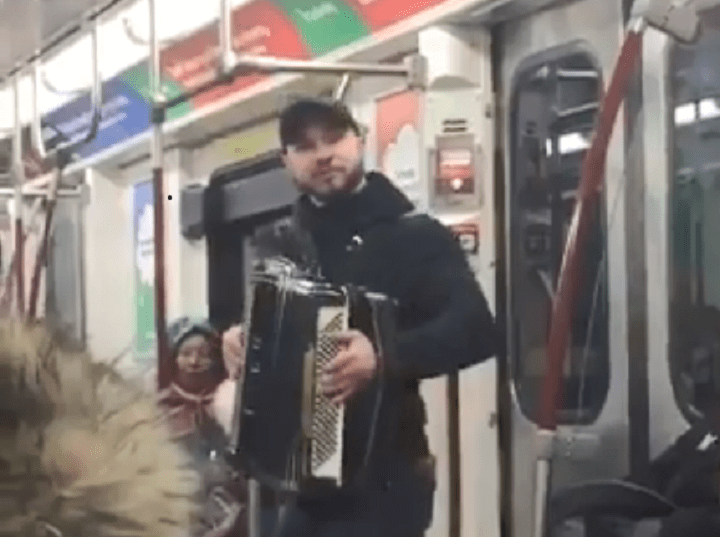 Accordion-playing man jumps from subway car to subway car playing 'Despacito.' .