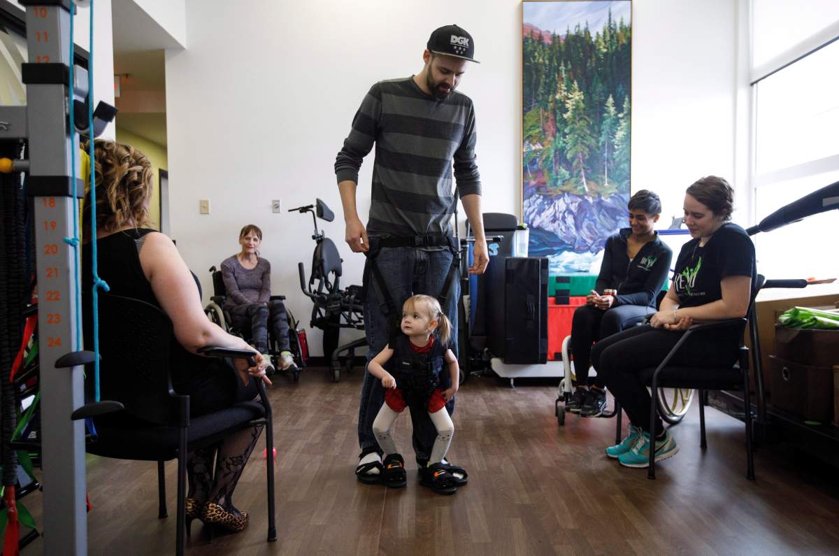 Evelyn Moore is hooked up to her dad Brad Moore as they take part in a walking exercise at the ReYu Paralysis Recovery Centre in Edmonton Alta, on Wednesday April 4, 2018.