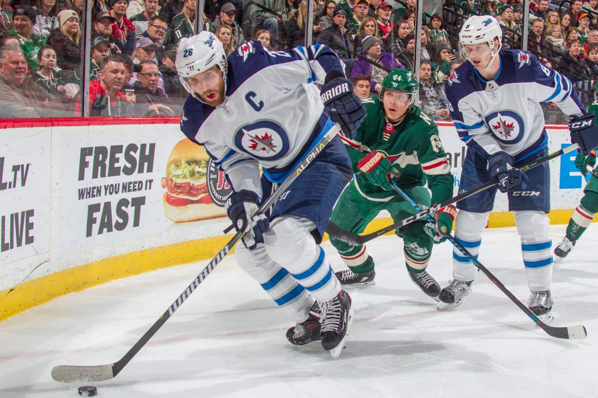 Blake Wheeler and Bryan Little of the Winnipeg Jets battle for the puck with Mikael Granlund of the Minnesota Wild during the game at the Xcel Energy Center on January 13, 2018 in St. Paul, Minnesota.