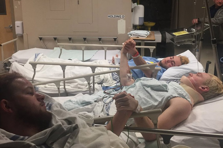 Three players from the Humboldt Broncos hold hands in hospital.