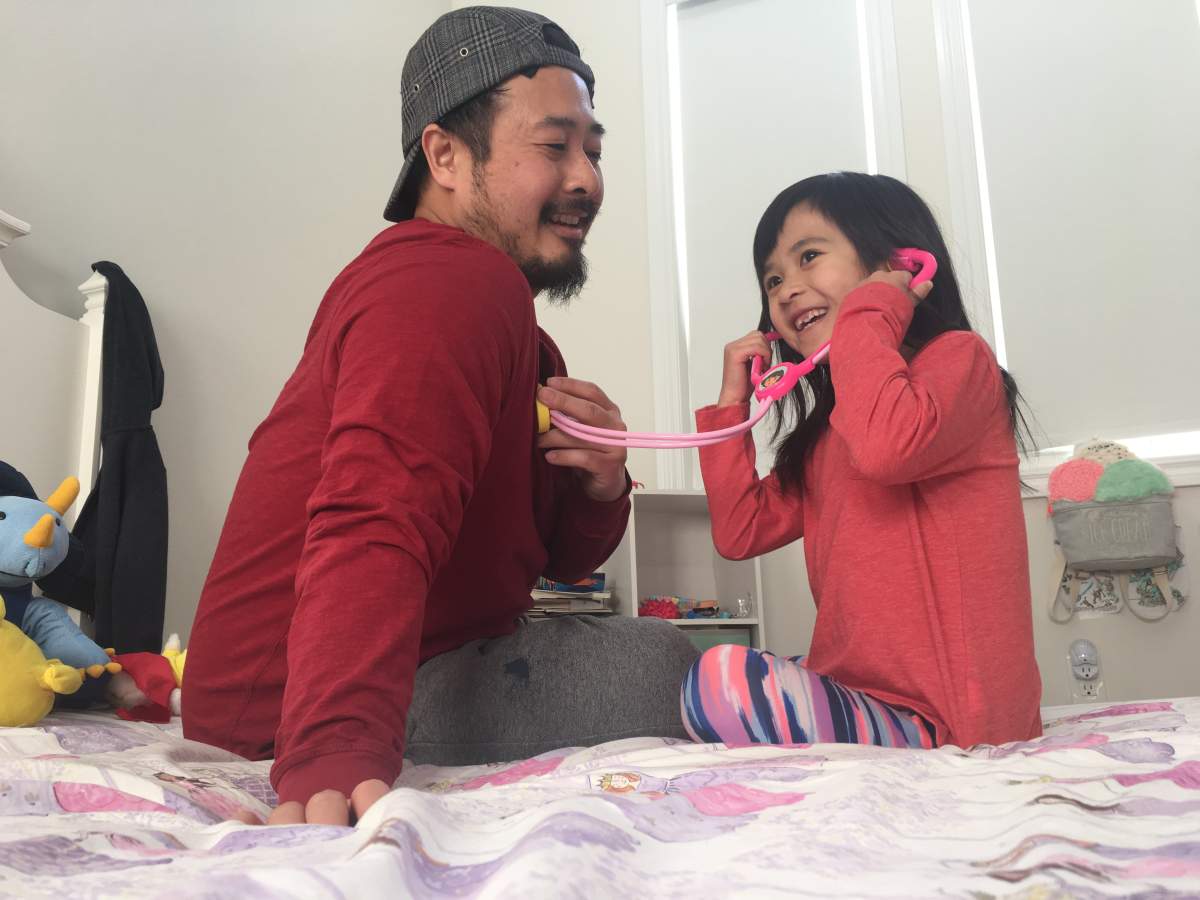 Olivia Chan (right) uses her play stethoscope to "listen" to the heartbeat of her father, Justin Chan (left). 